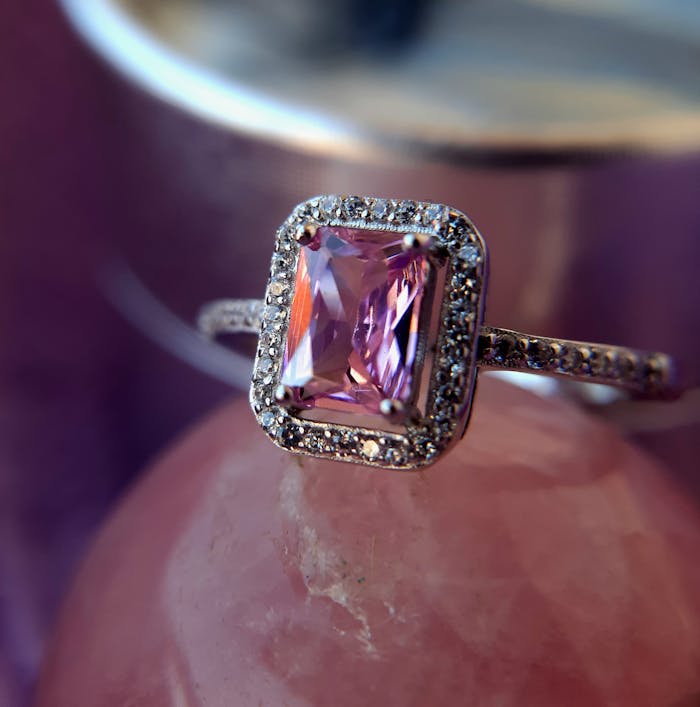Close-up of a silver ring featuring a pink gemstone, highlighting its intricate design in soft lighting.